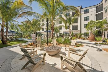 A patio with chairs and a fire pit in front of a building